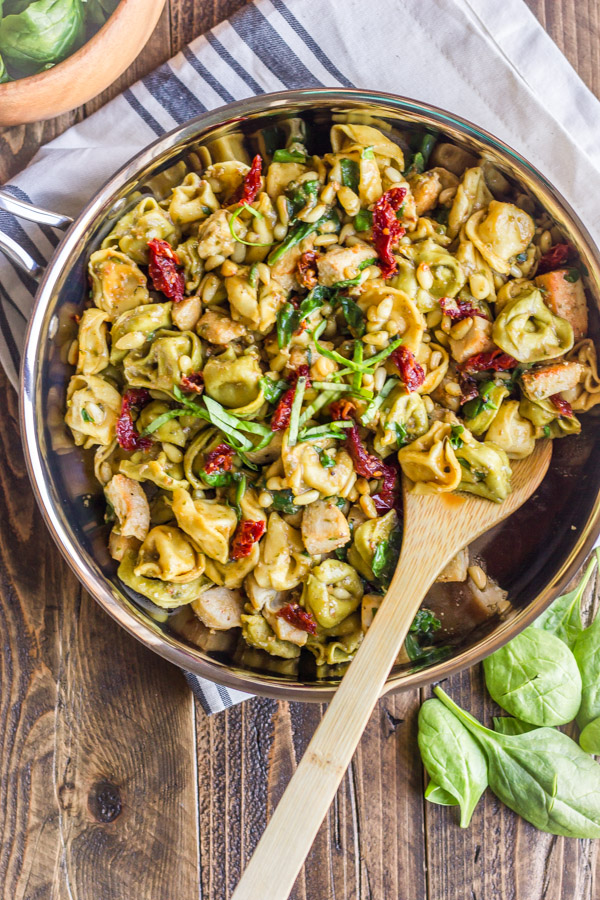 One Skillet Chicken Tortellini in a skillet with a wooden spoon.  