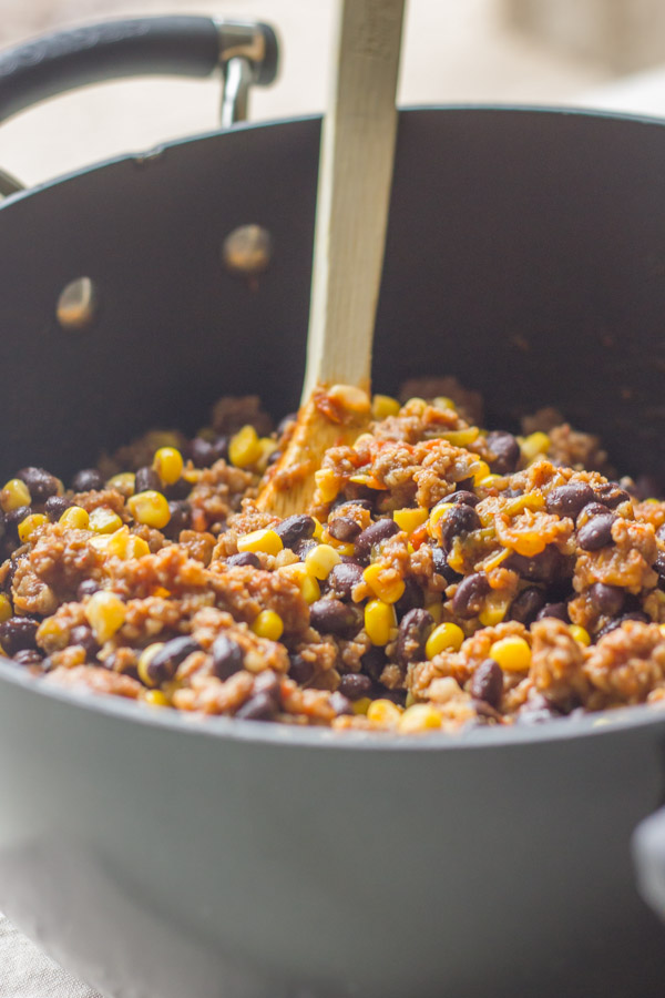 A pot with sausage, spices, black beans, corn and salsa for the Homemade Chili Queso.