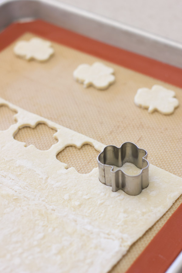 Puff pastry on a Silpat lined baking sheet, with a shamrock cookie cutter making the Shamrock Croutons. 