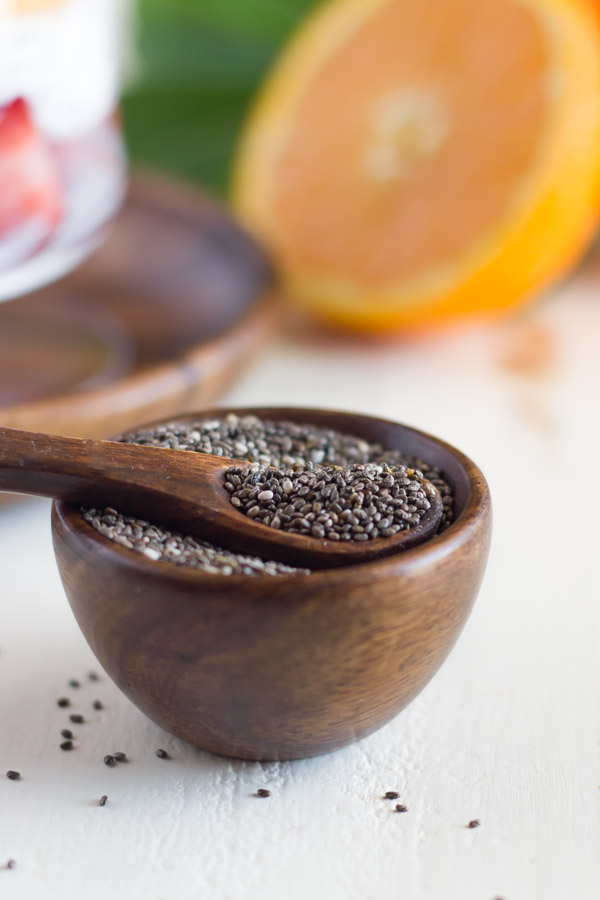 A small wood bowl of chia seeds with a tiny spoon in it.  