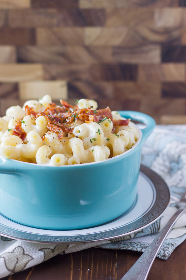 Creamy Mac and Cheese With Bacon in a bowl that is sitting on a plate. 