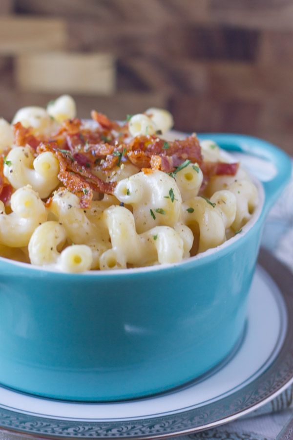 Creamy Mac and Cheese With Bacon in a bowl that is sitting on a plate.  