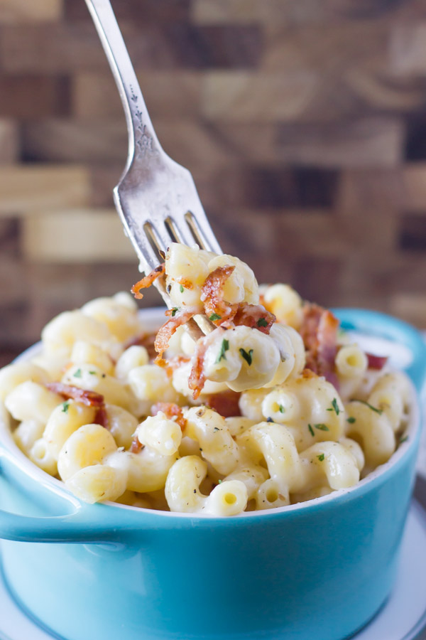 Creamy Mac and Cheese With Bacon in a bowl, with a fork full of the mac and cheese over the bowl.  
