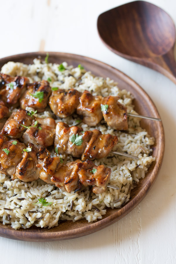 Maple Dijon Glazed Chicken served over a bed of rice on a wood plate.  