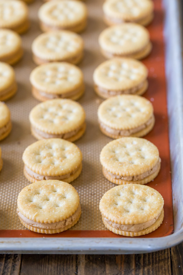 A Silpat lined baking sheet full of the Ritz crackers with peanut butter filling sandwiches. 