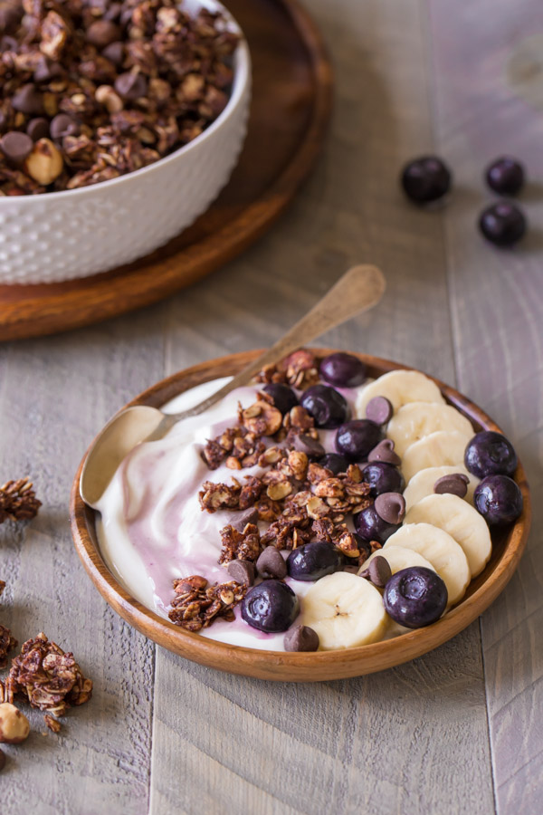 Chocolate Hazelnut Granola Yogurt Bowl with a spoon in it, with a bowl of granola in the background.  