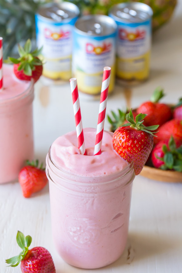 Dole Pineapple Strawberry Cream Slush in a glass jar, with two straws and a strawberry on the rim of the jar. 