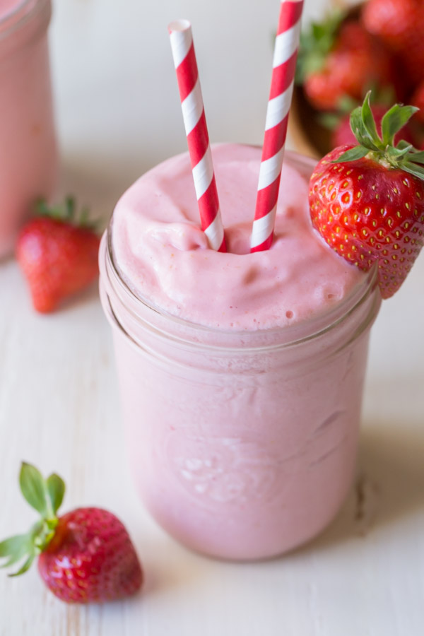 Dole Pineapple Strawberry Cream Slush in a glass jar, with two straws and a strawberry on the rim of the jar. 