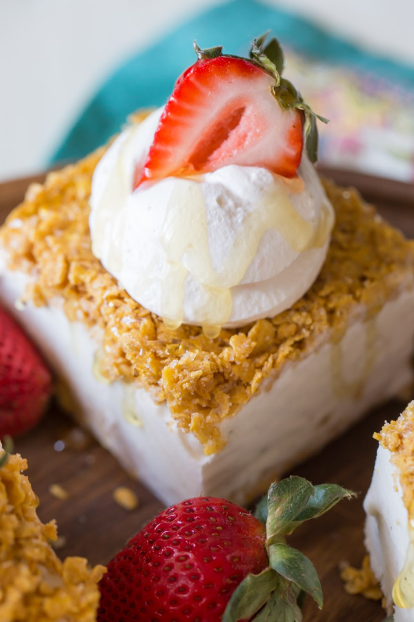 Fried Ice Cream Bar topped with whipped cream, a sliced strawberry and some honey.  
