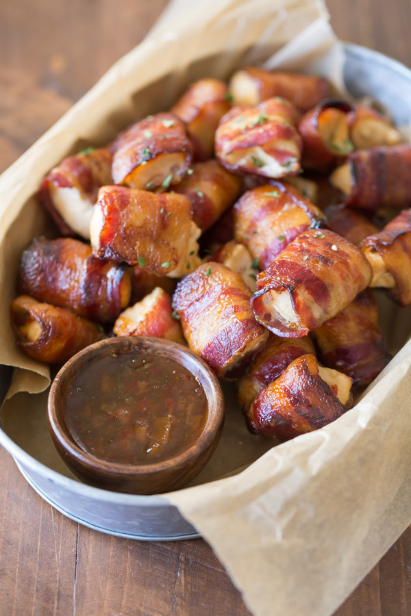 Bacon Wrapped Chicken Bites in a galvanized serving bucket with a little cup of Apricot Pepper Dipping Sauce.