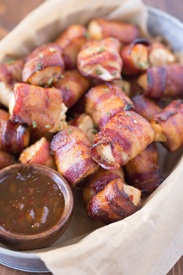Bacon Wrapped Chicken Bites in a galvanized serving bucket with a little cup of Apricot Pepper Dipping Sauce.