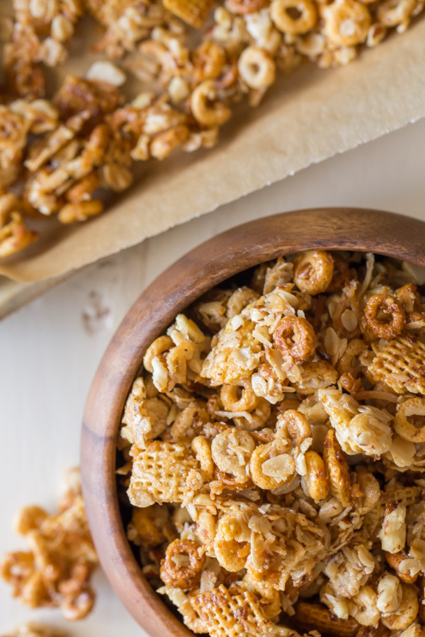 Healthier Coconut Almond Chex Mix in a wood bowl with more Chex mix on a parchment paper lined baking sheet next to the bowl.    