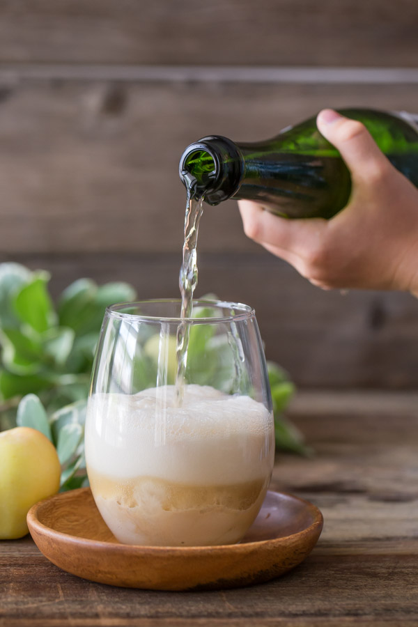 A glass with Salted Caramel Ice Cream in it, and some Sparkling Apple Cider being poured on top.  