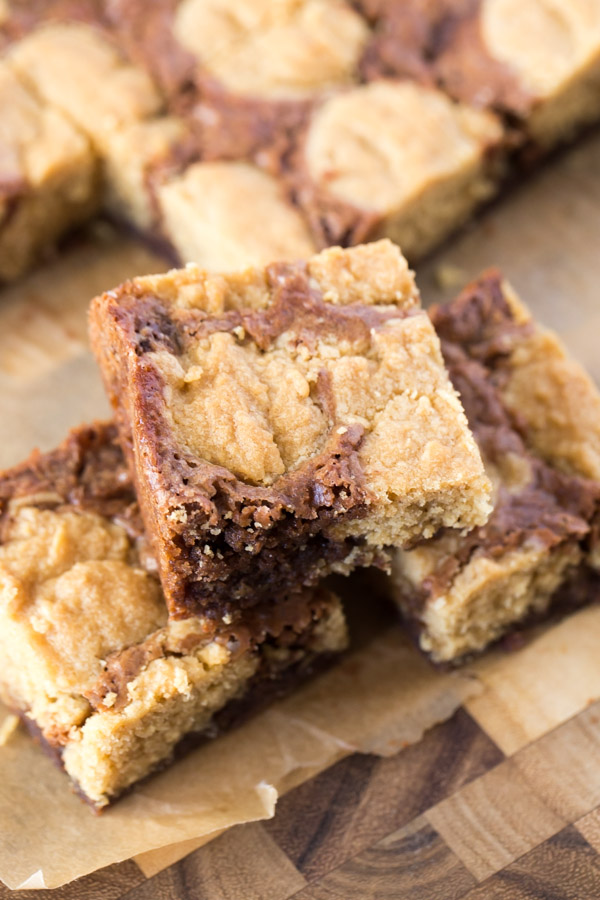 Three Peanut Butter Cookie Brownies stacked, with more brownies in the background. 