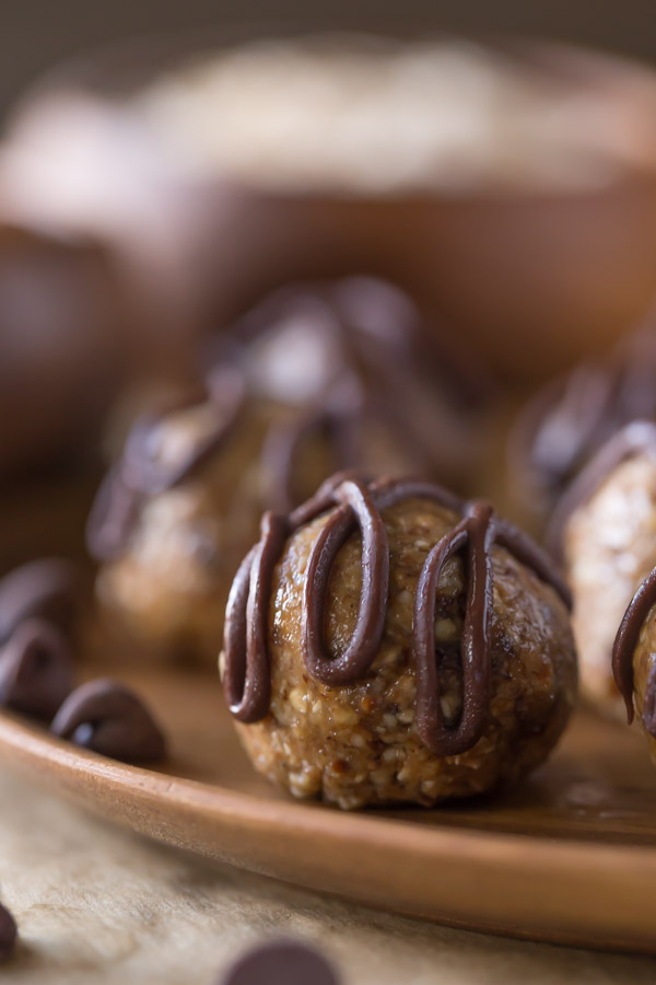 No Bake Energy Bites on a wood plate, drizzled with melted chocolate. 