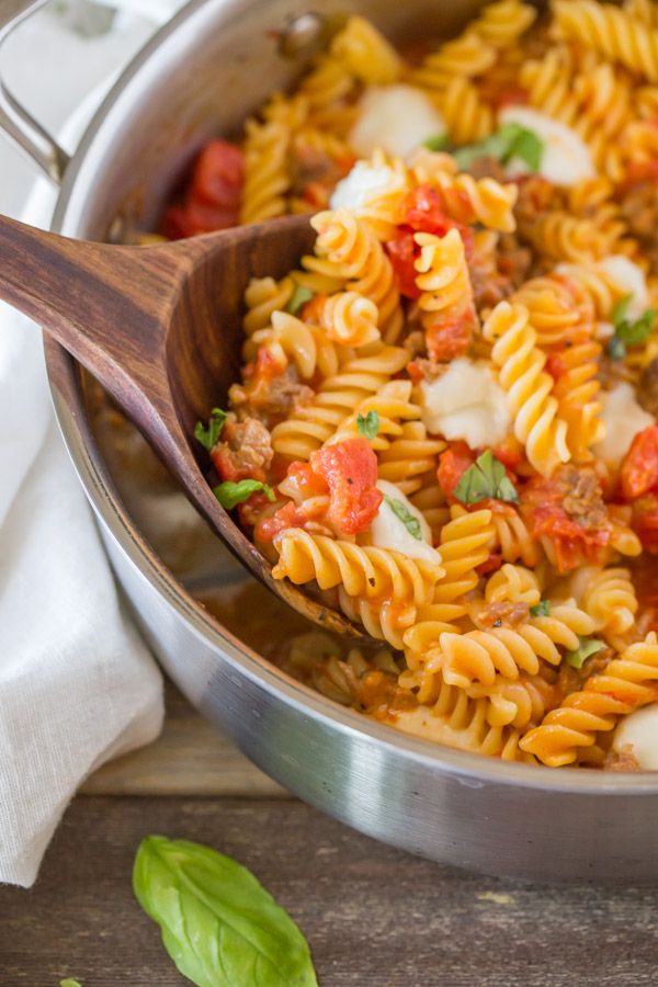 One Pot Fusilli With Tomato, Basil, and Mozzarella in a large pan with a wood serving spoon.  