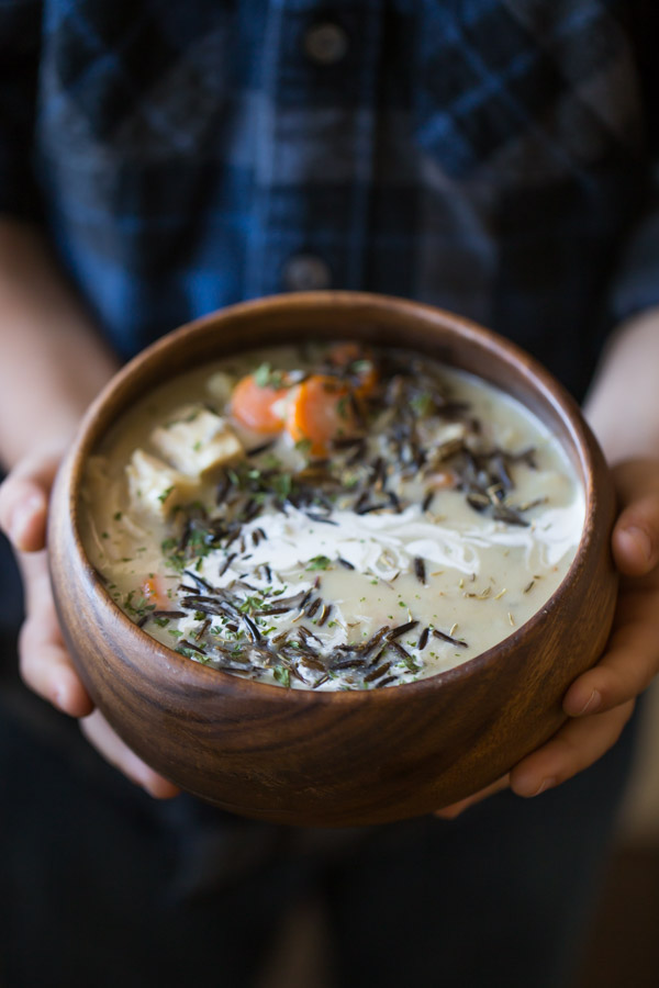 Creamy Chicken and Wild Rice Soup in a wood bowl, being held by a child.  