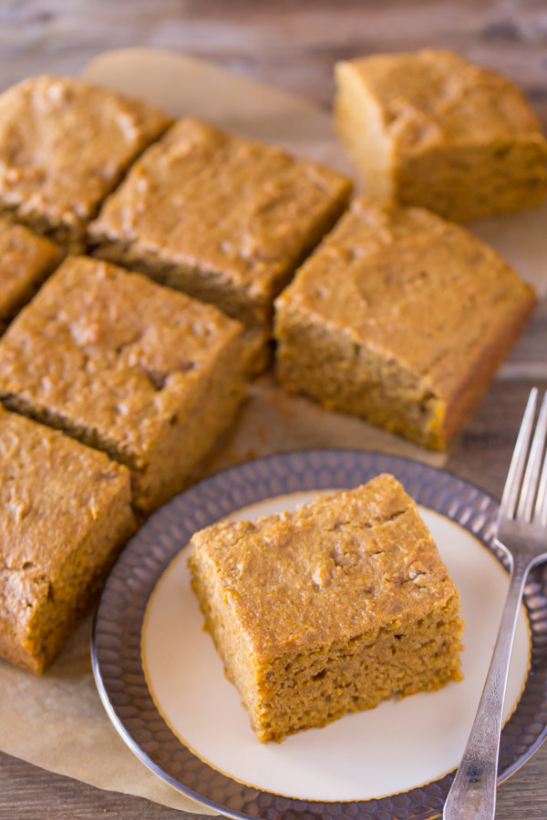 Healthier Pumpkin Spice Snack Cake cut into square pieces, with one piece on a plate with a fork.  