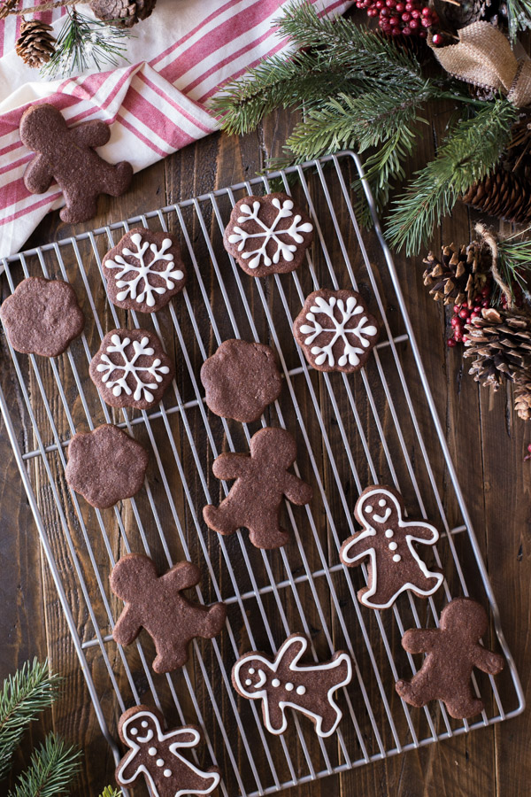 A cooling rack with Snowflake and Gingerbread Men Chocolate Cut-Out Cookies, with some decorated with icing. 