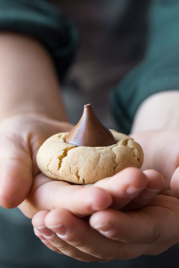 One No Shortening Peanut Butter Blossom sitting in a child's hands.  