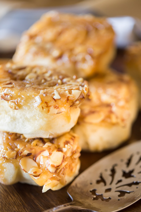 Almond Sticky Buns stacked in piles of two, sitting next to a serving spatula.  