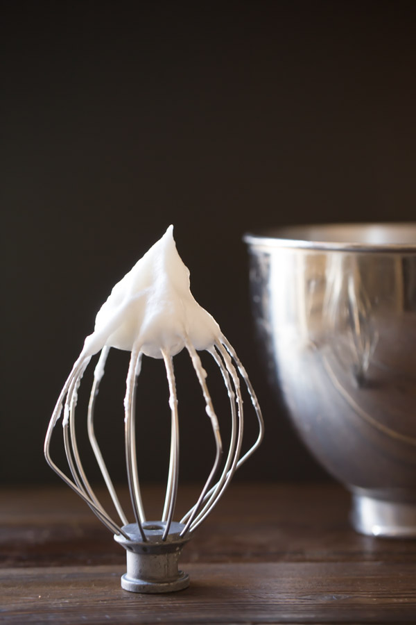 The whisk from the electric mixer showing a soft peak of whipped cream.  