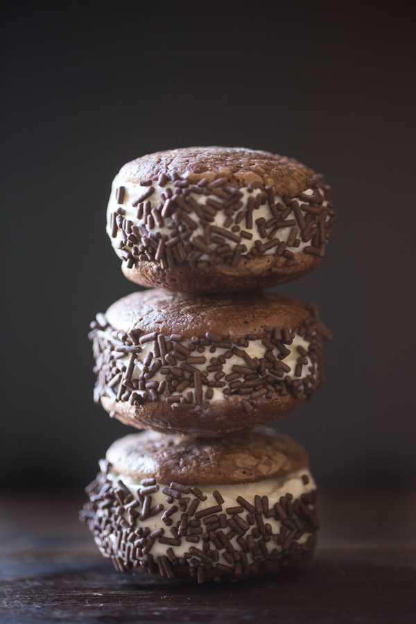 Three Brownie Cookie Ice Cream Sandwiches with chocolate sprinkles stacked on top of each other.  