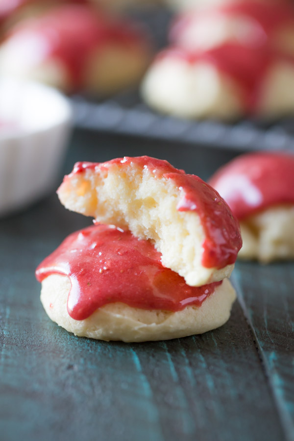 A half of a Strawberry Glazed Ricotta Cookie stacked on top of a whole Strawberry Glazed Ricotta Cookie.