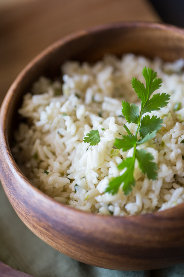 A wood bowl of Cilantro Lime Rice garnished with some fresh cilantro. 