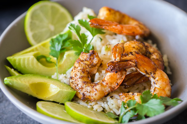 Cilantro Lime Rice Shrimp Bowl garnished with lime slices, avocado slices and fresh cilantro.