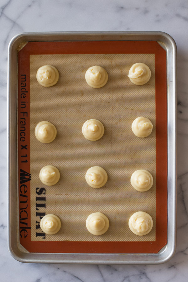 Classic Cream Puff dough that has been piped onto a Silpat lined baking sheet. 