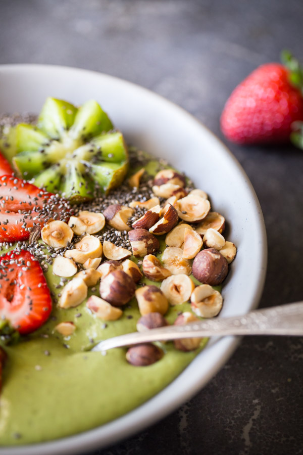 Strawberry Kiwi Protein Smoothie Bowl topped with sliced fresh strawberries and kiwi, hazelnuts, and chia seeds.