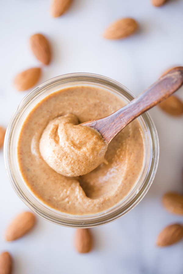Homemade Almond Butter in a small glass jar with a tiny wood spoon in it.  
