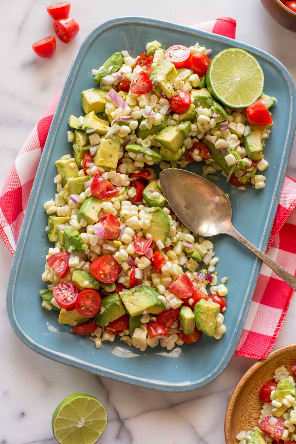 Corn, Tomato, and Avocado Salad on a platter with a serving spoon.