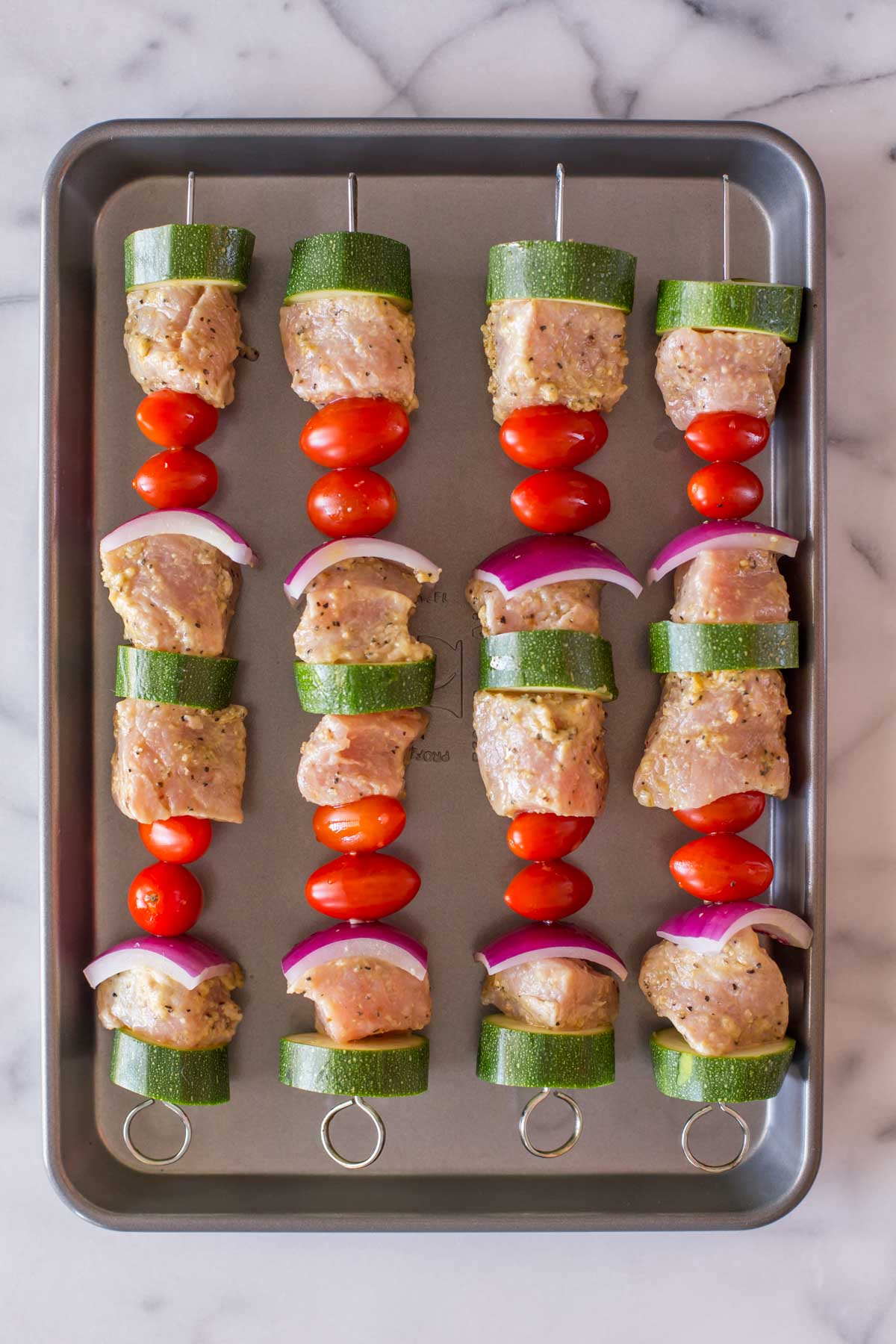 Pork Tenderloin Kabobs on a baking sheet before being grilled.  