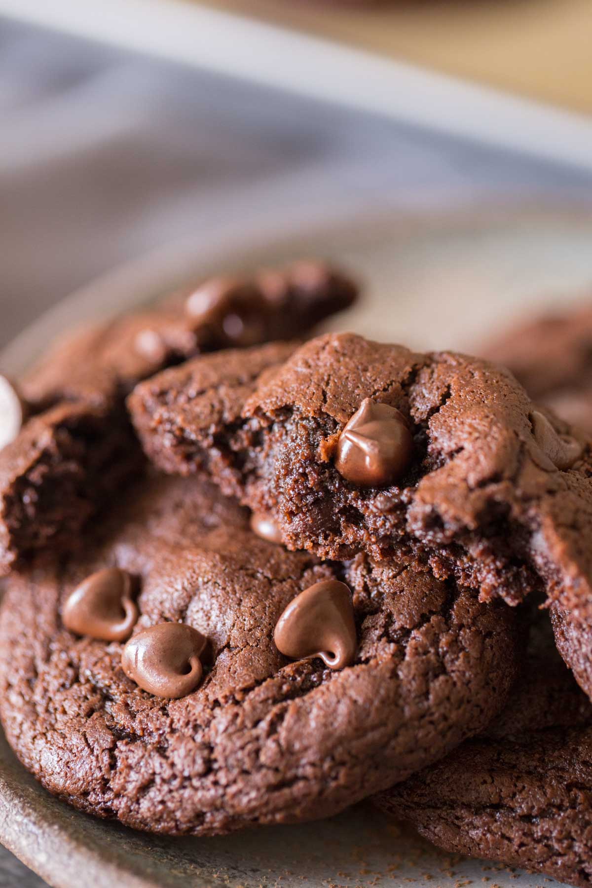 A plate of One Bowl Triple Chocolate Brownie Cookies, with one of the cookies broken in half. 
