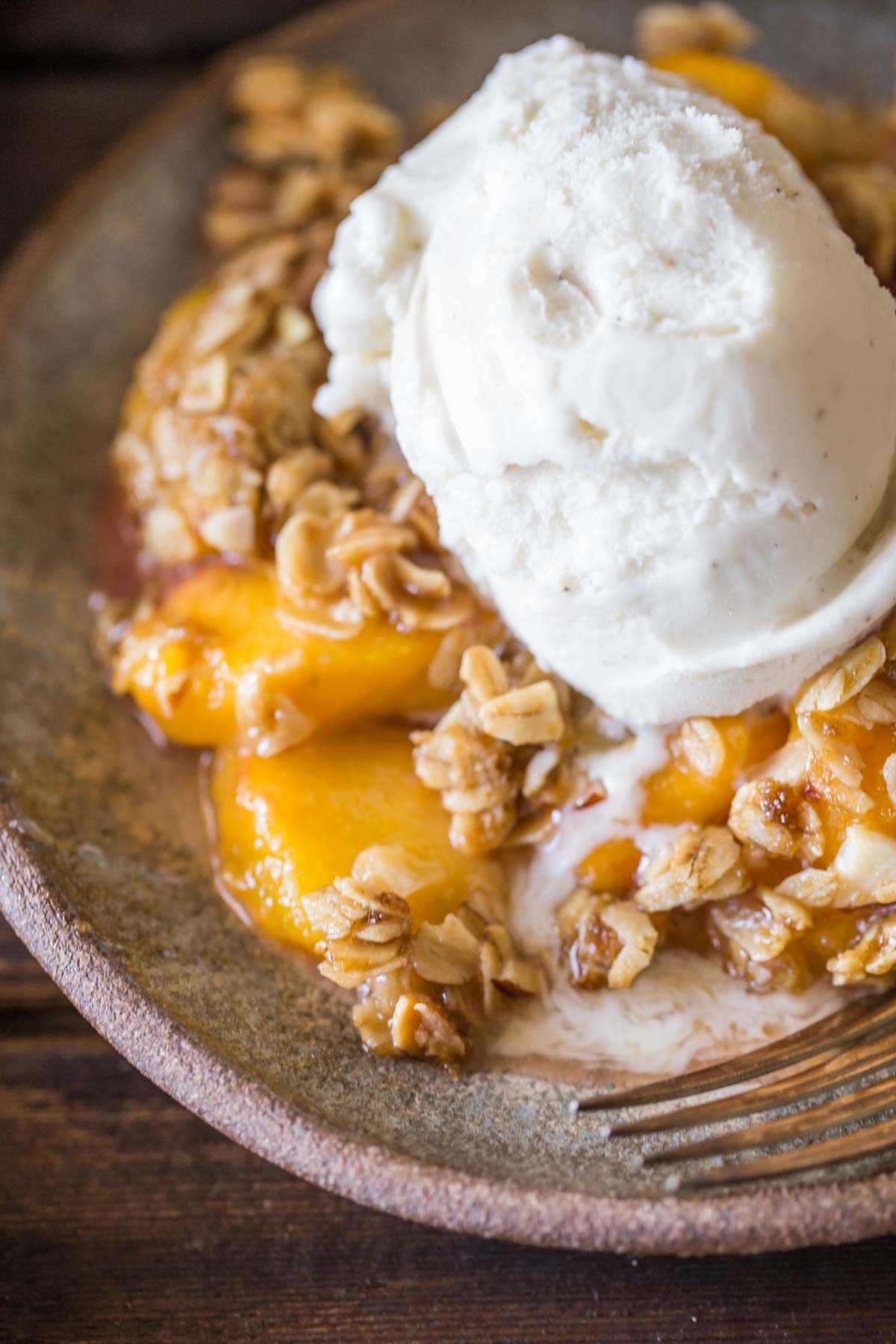 A plate of Easy Skillet Peach Crisp topped with vanilla ice cream.