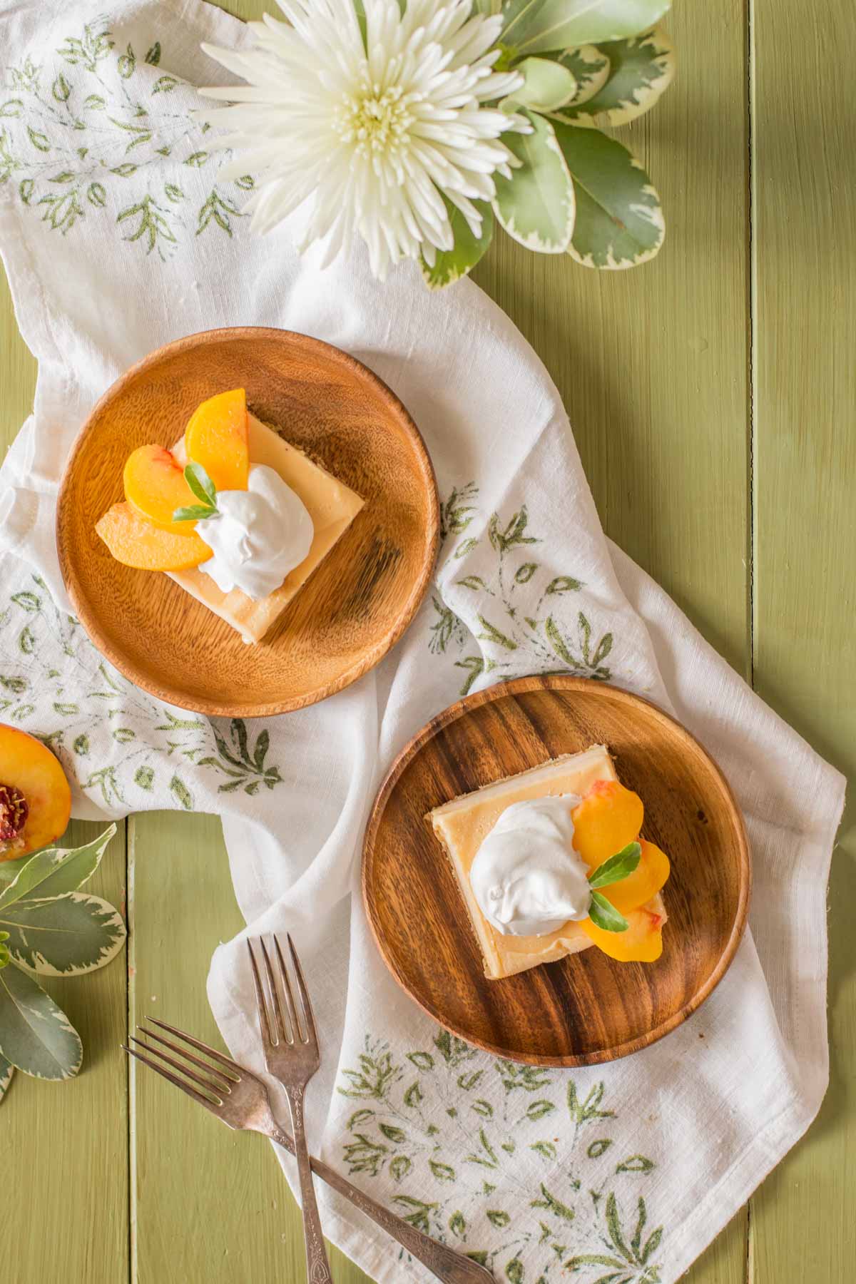 Two wood plates, each with an Easy Homemade Peach Ice Cream Bar on it, topped with whipped cream and fresh peach slices. 