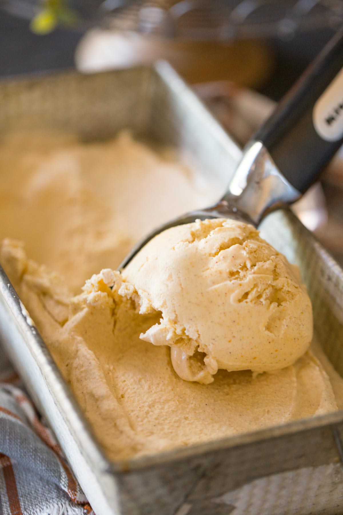 Homemade Pumpkin Pie Ice Cream being scooped from a loaf pan container. 