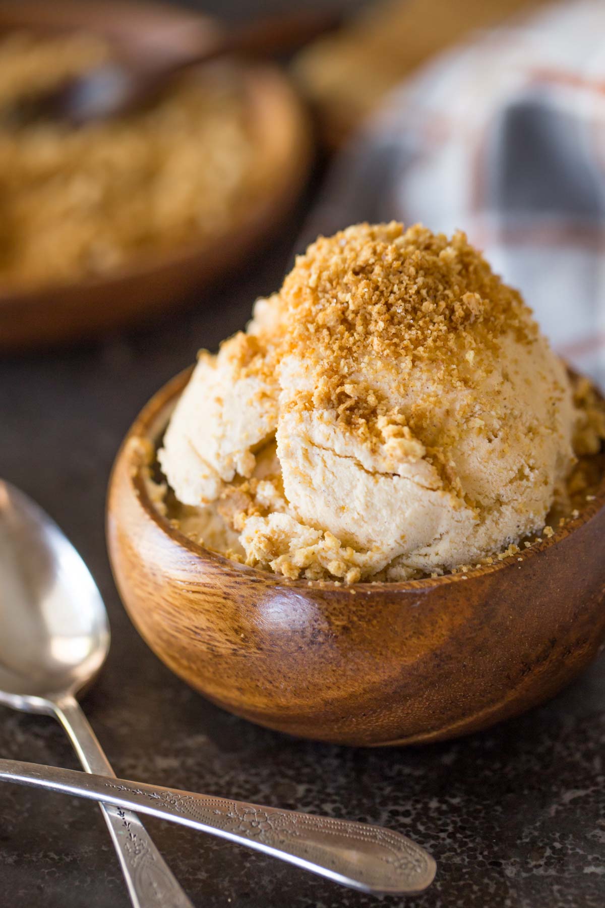 Homemade Pumpkin Pie Ice Cream in a wood bowl, topped with crushed graham cracker crumbs.
