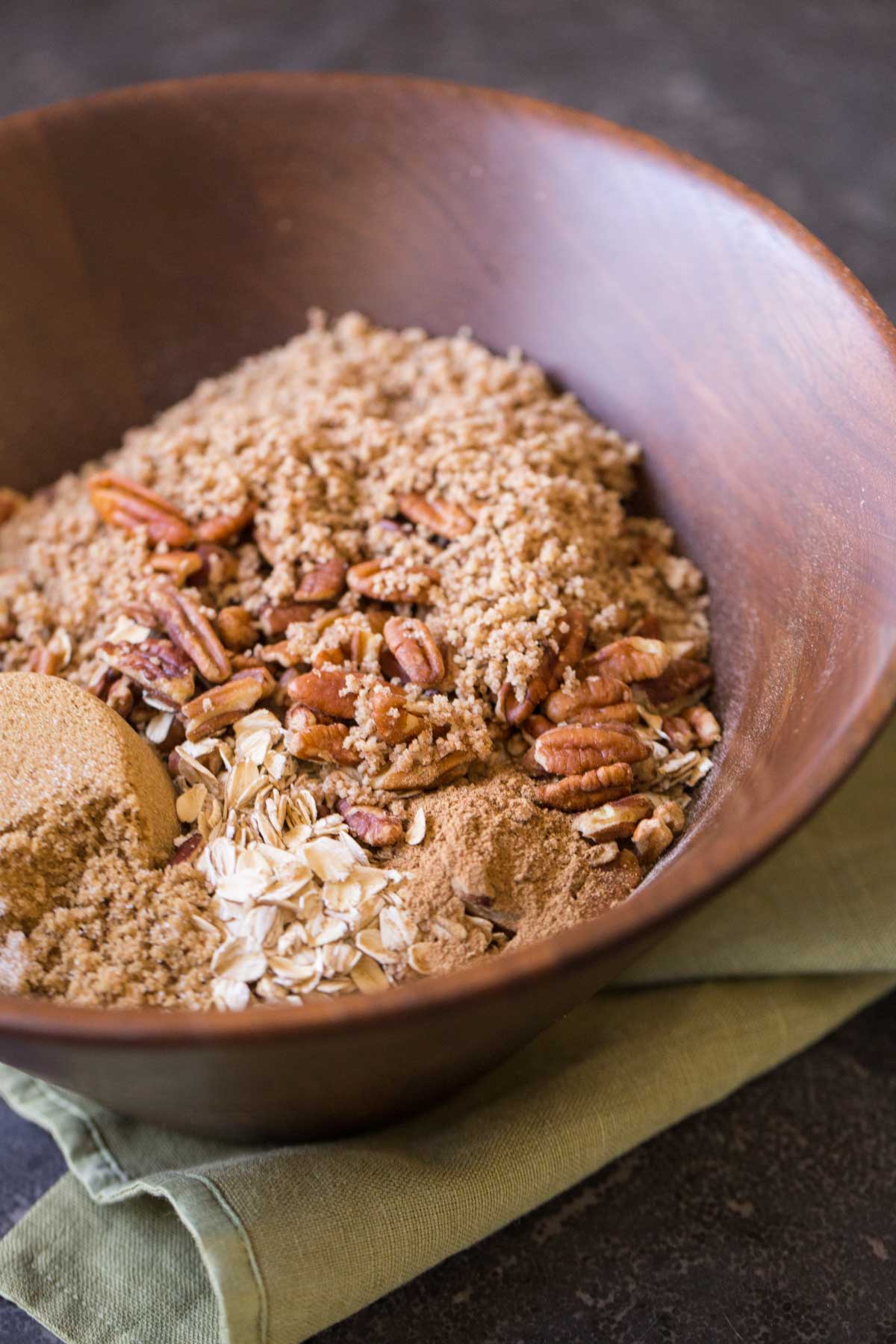 Ingredients for the Gingerbread Spice Granola in a large wood mixing bowl. 