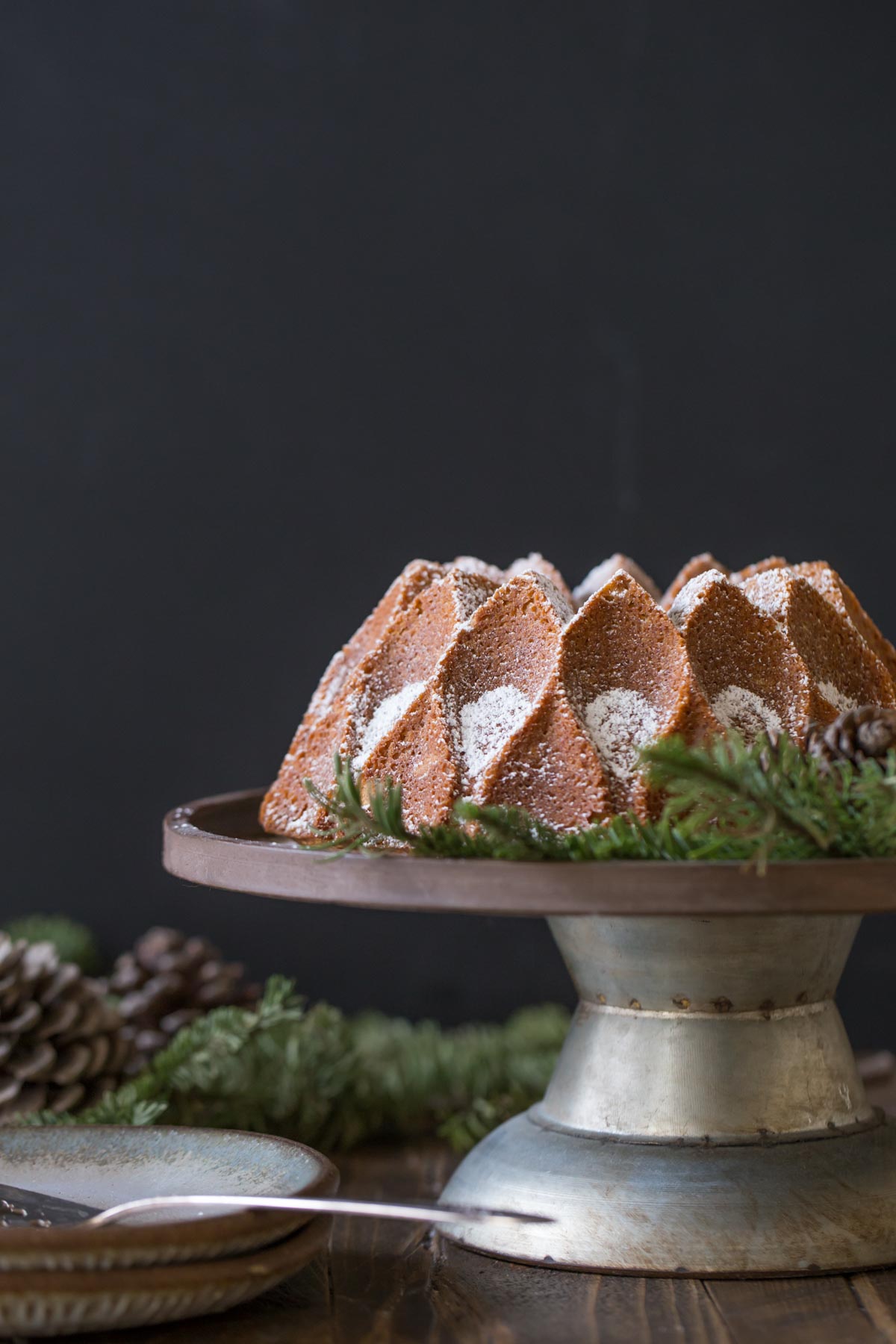Gingerbread Bundt Cake on a cake stand, dusted with powdered sugar. 