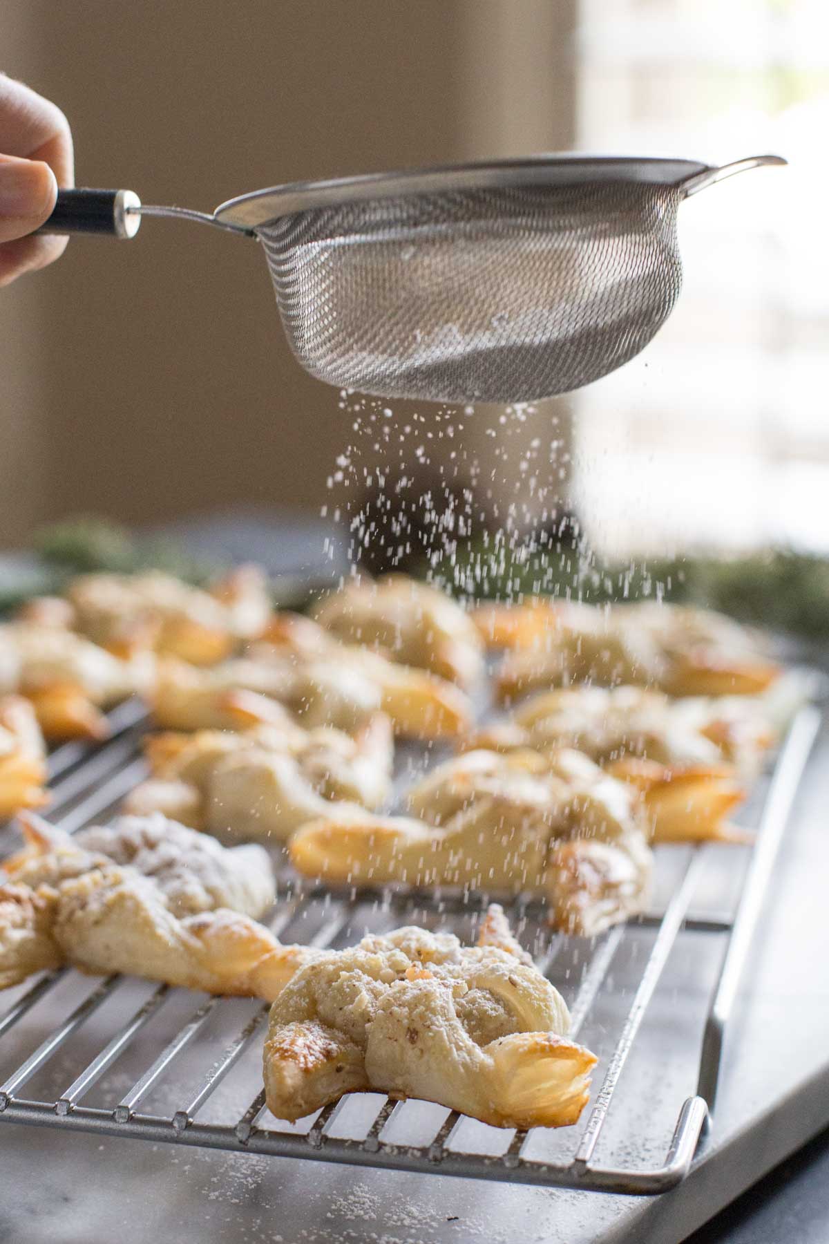 Make Ahead Almond Pinwheels on a cooling rack, being sprinkled with powdered sugar. 