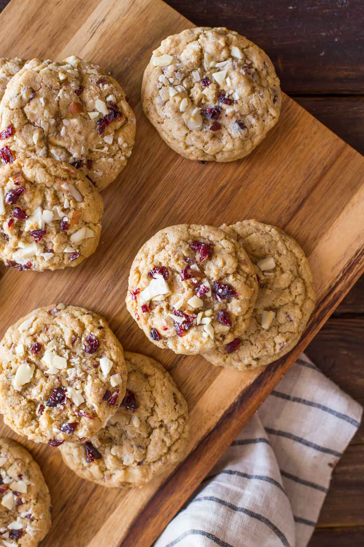 Cranberry Almond White Chocolate Chunk Cookies on a wood cutting board. 