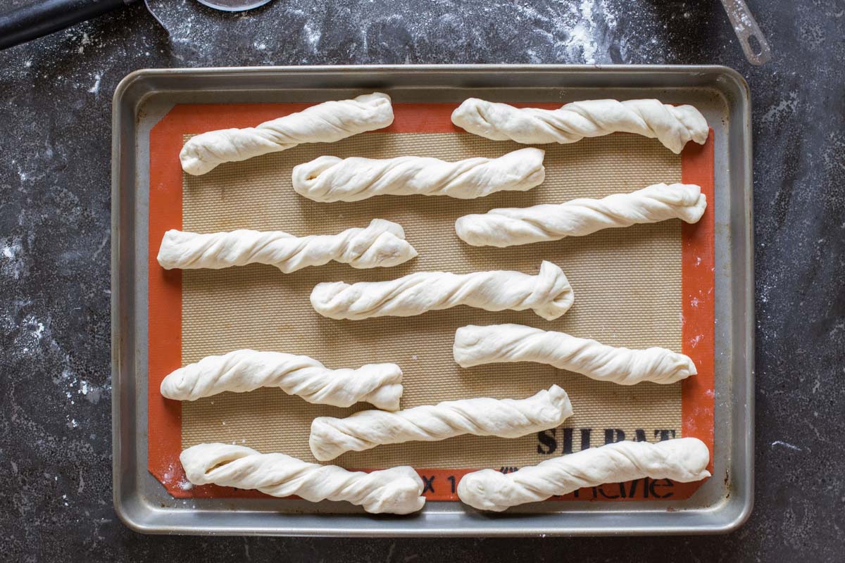 Fresh Buttery Garlic Breadsticks dough twisted on baking sheet.