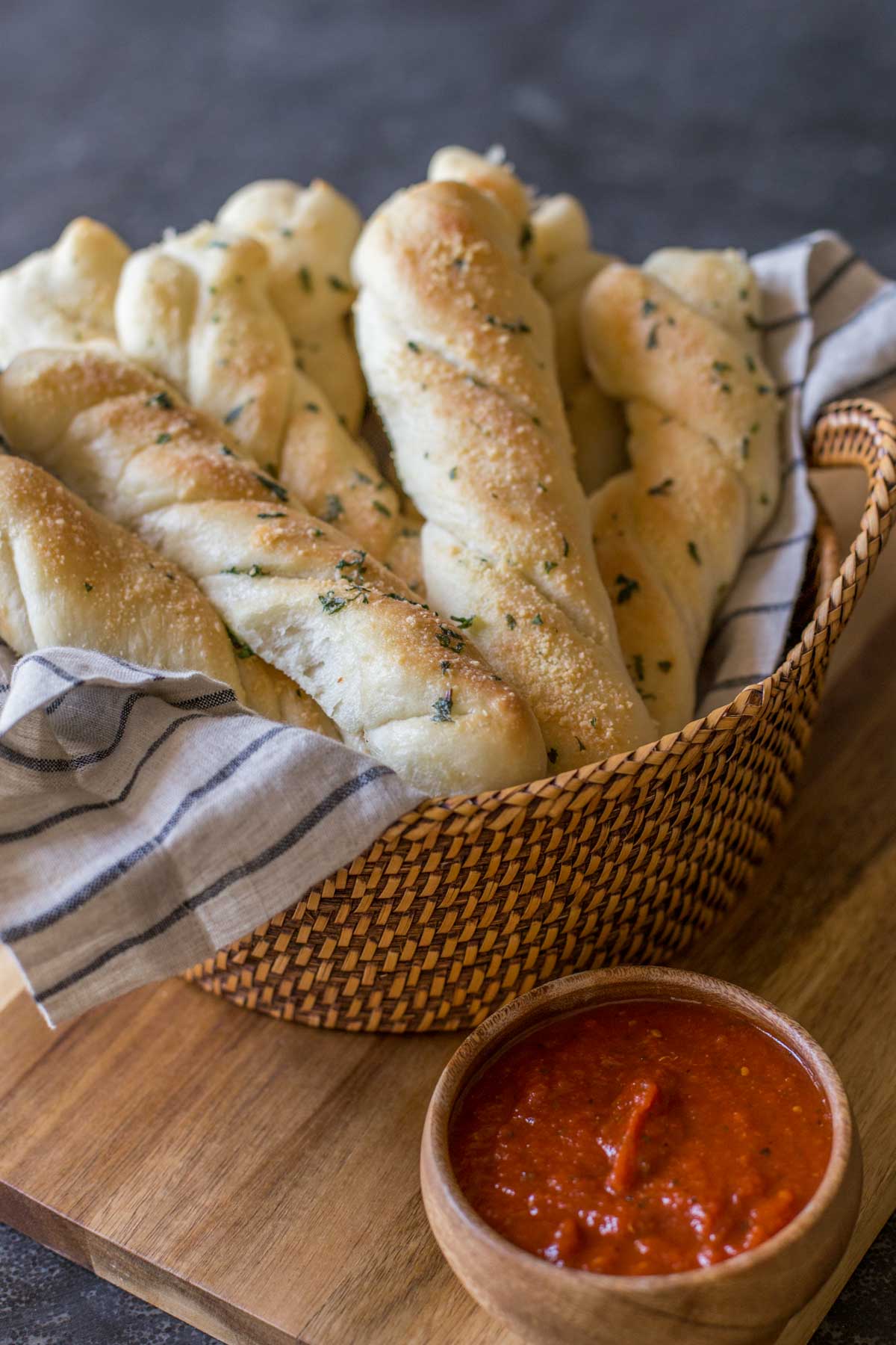 Fresh Buttery Garlic Breadsticks in a basket with marinara in a dipping bowl.