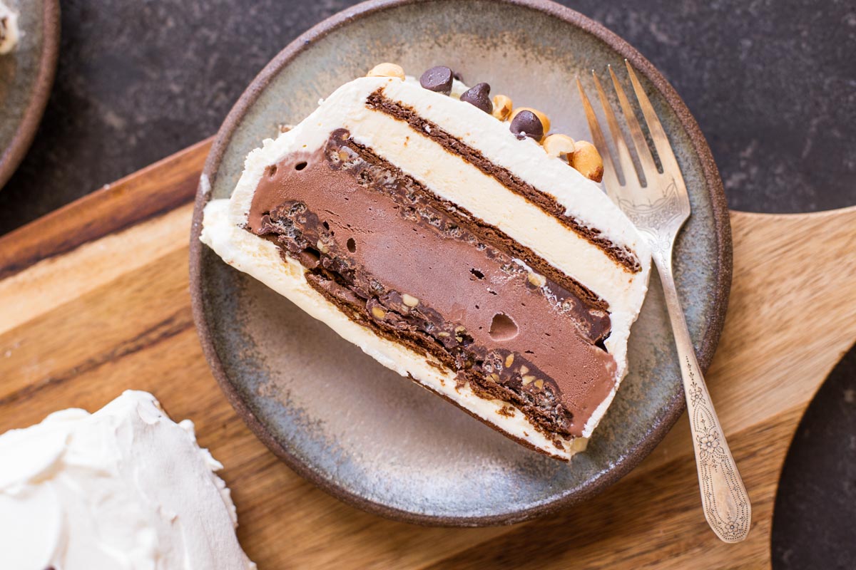 A slice of Chocolate Peanut Butter Ice Cream Slice Cake on a plate with a fork.  