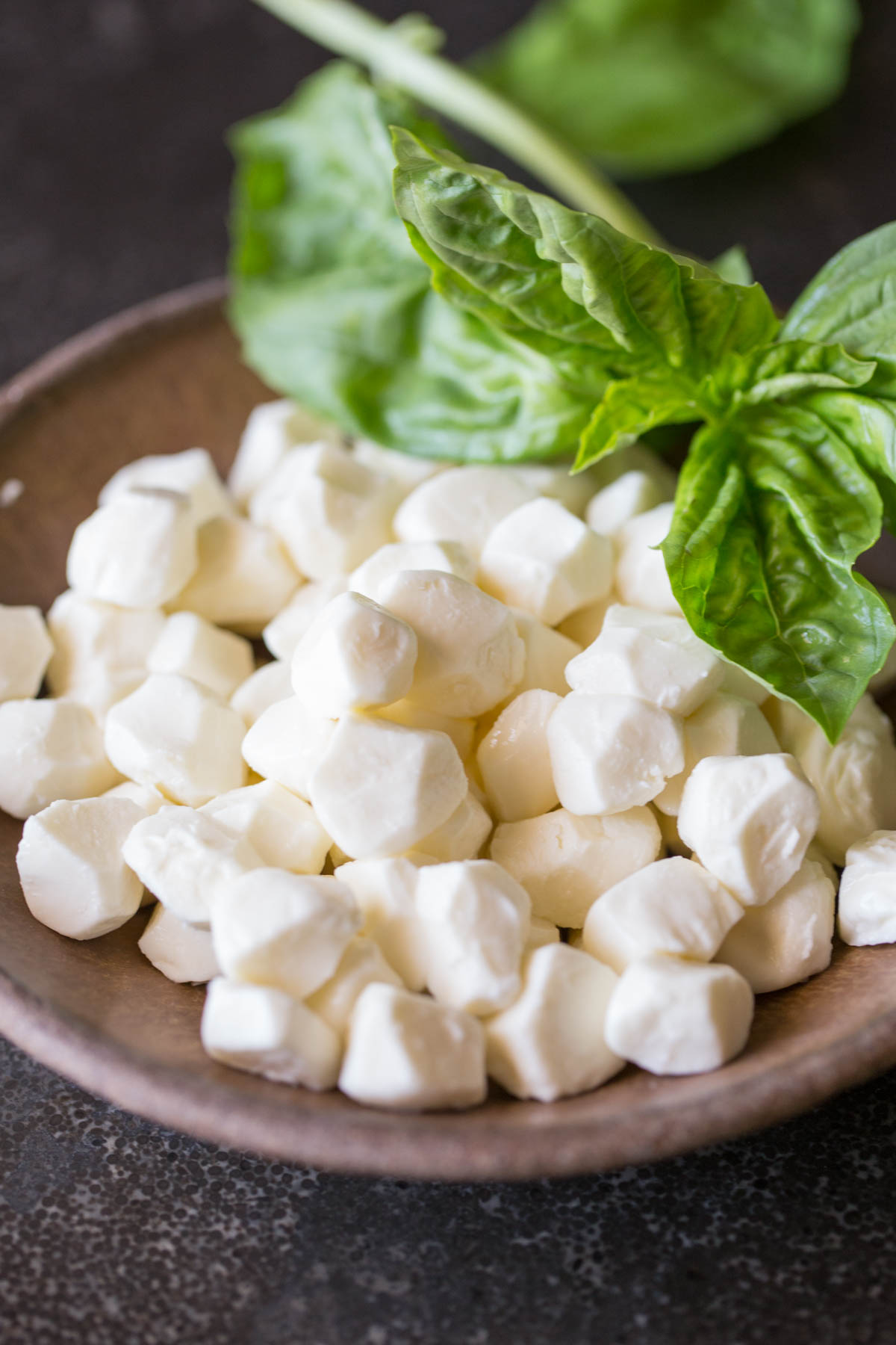 A bowl of fresh mozzarella pearls with some fresh basil for the Pesto Chicken Skillet.