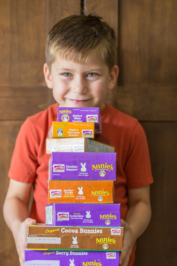 Little boy holding a stack of various Annie's products. 