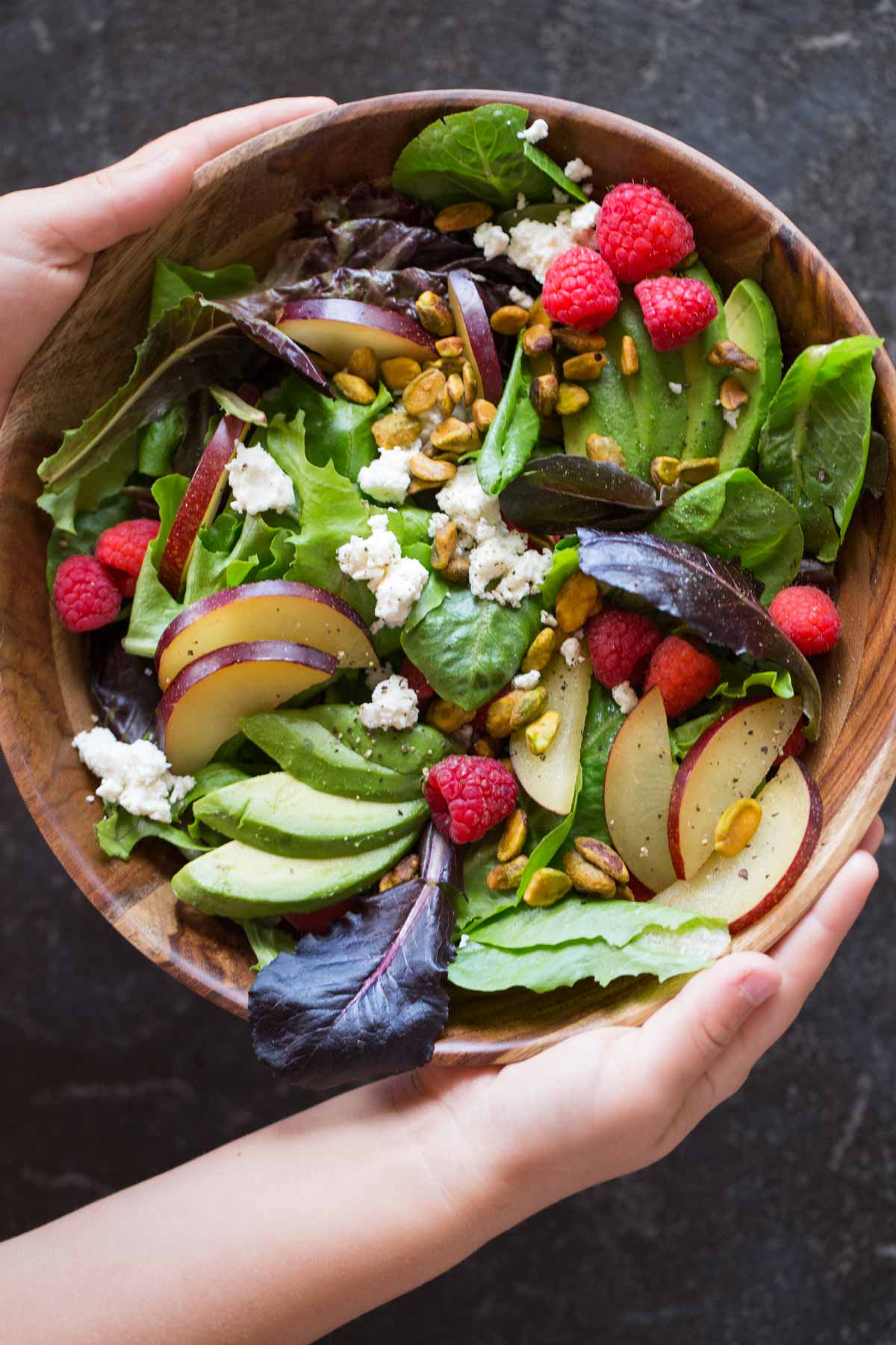 Summer Fruited Salad with Goat Cheese and Pistachios in a wood bowl.  